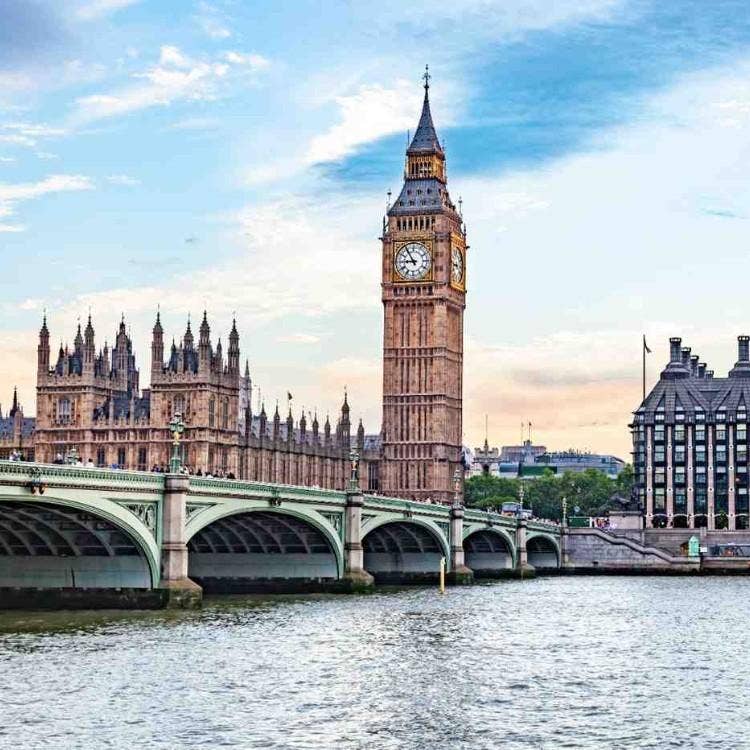 The iconic Big Ben clock tower and the Palace of Westminster standing tall next to Westminster Bridge over the River Thames.