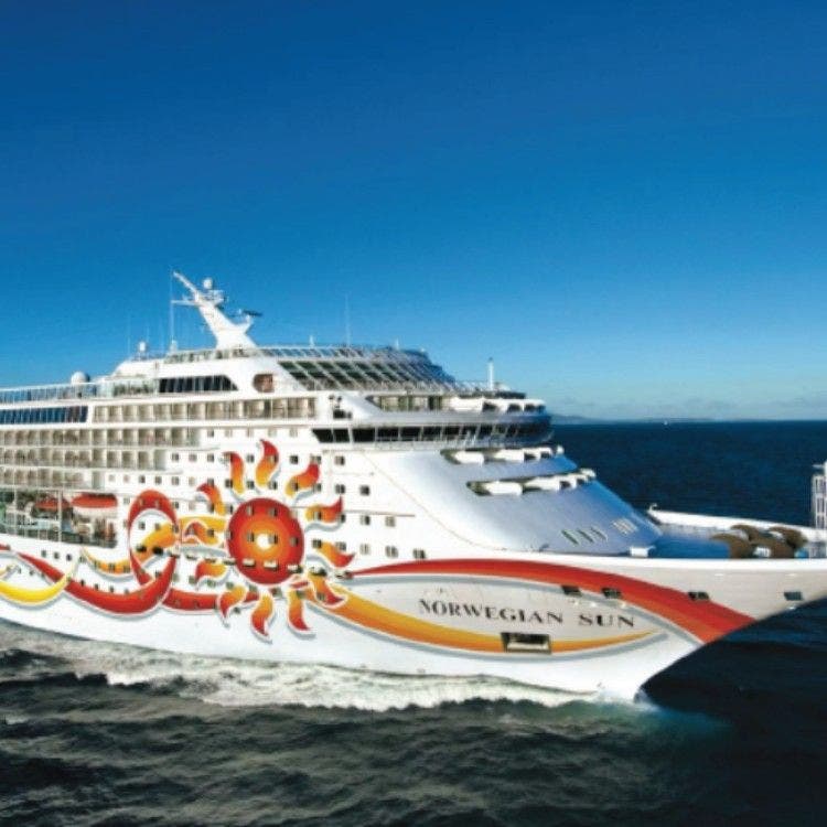 The cruise ship Norwegian Sun, showcasing its distinct sun-themed hull artwork, sailing through calm blue waters for the Transatlantic Crossing section.