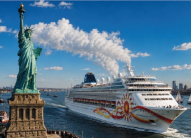 The cruise ship Norwegian Sun sailing past the Statue of Liberty into New York Harbor under a bright blue sky for the Canada to United States section.